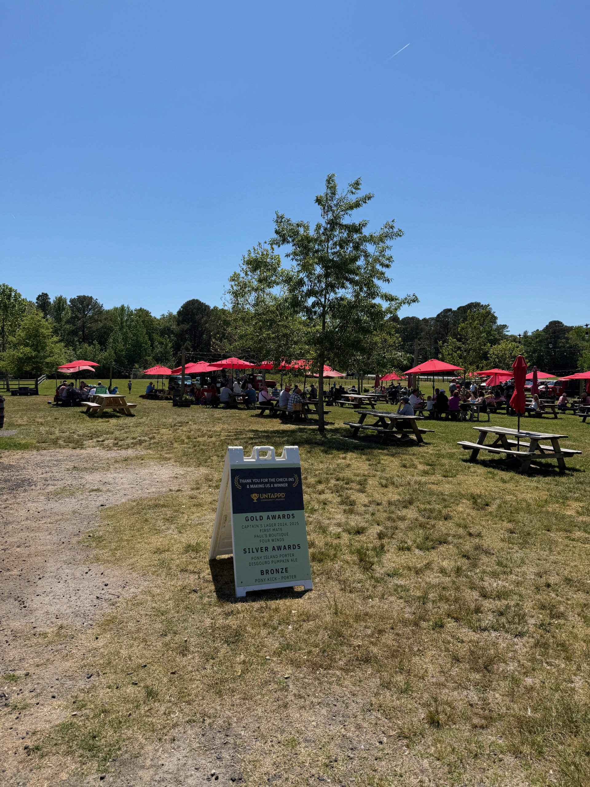 The Sinepuxent Brewing scene in Berlin: picnic tables, red umbrellas, cornhole. Universally good vibe.